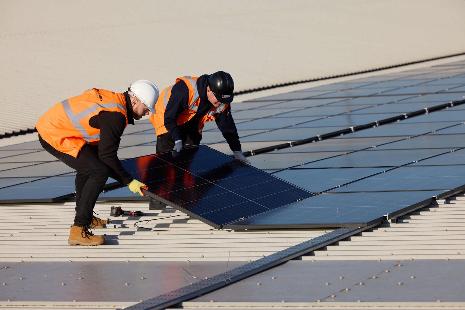 Crew lifting a solar panel during a roof job